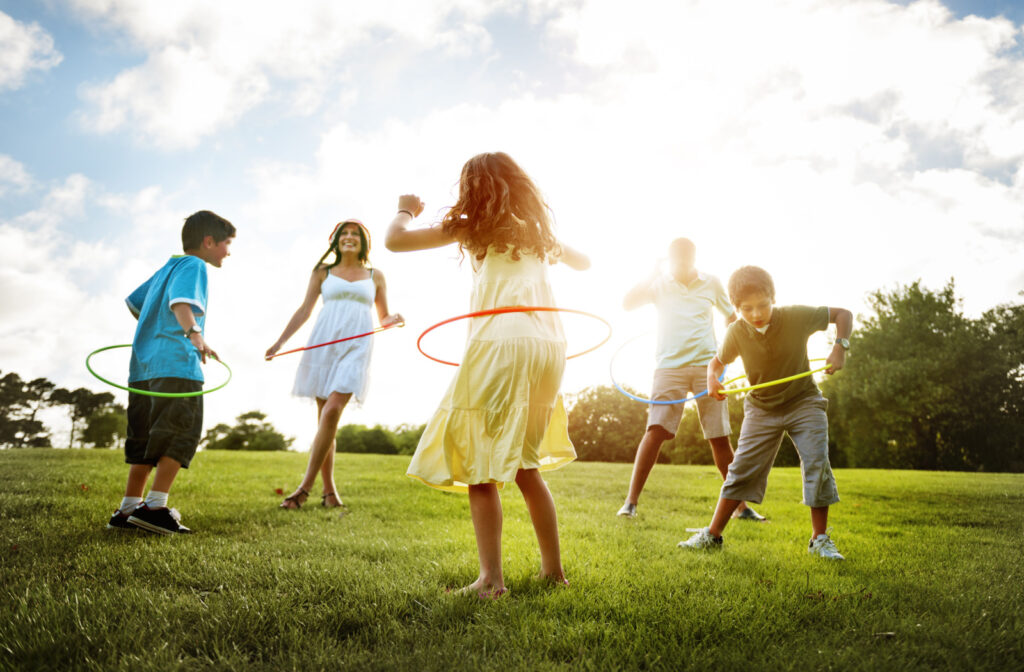 A family of five is having fun doing Hoola hoops, and practicing an active lifestyle outdoors