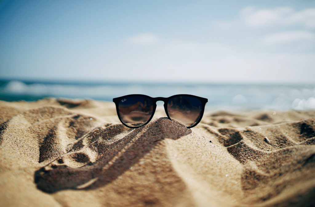 A pair of sunglasses sitting in the sand at a beach