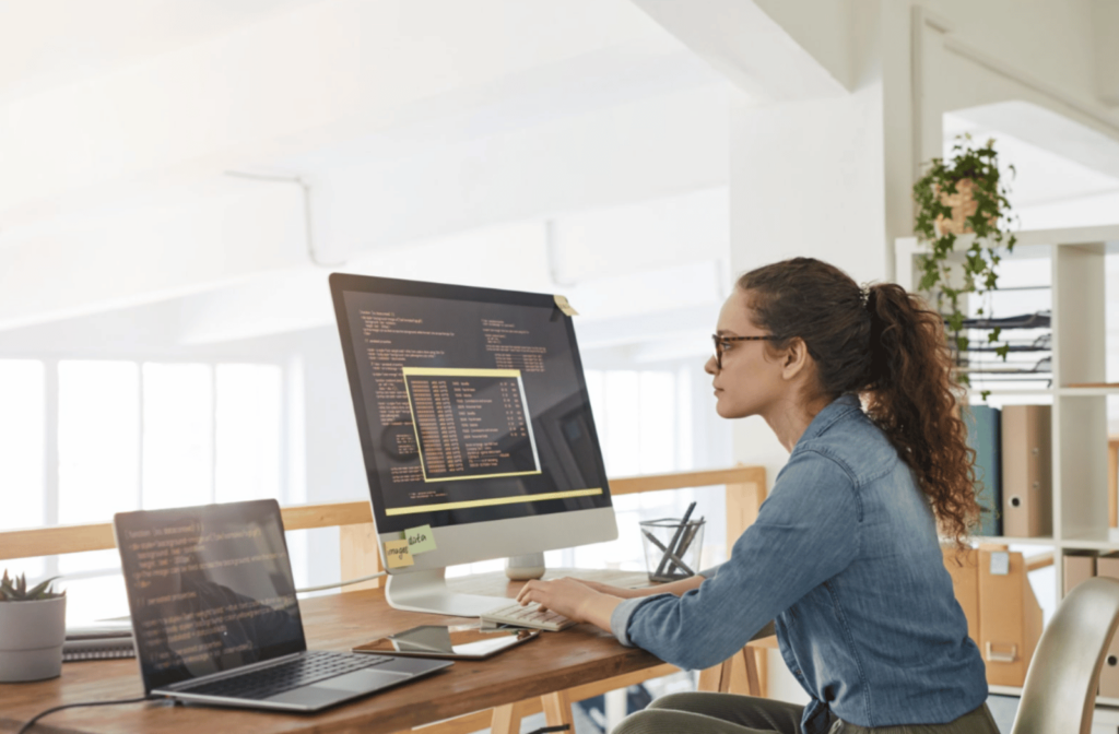 A young woman looking at her computer desktop screen, which is set to dark mode