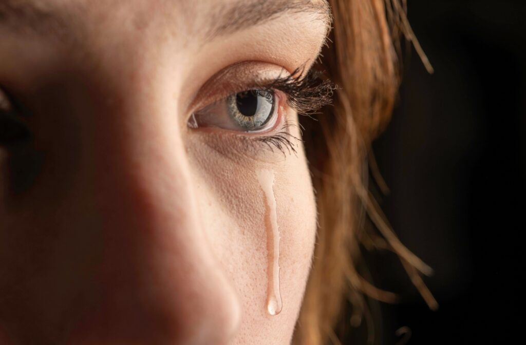 A close-up of a person's left eye with a tear rolling down their cheek.