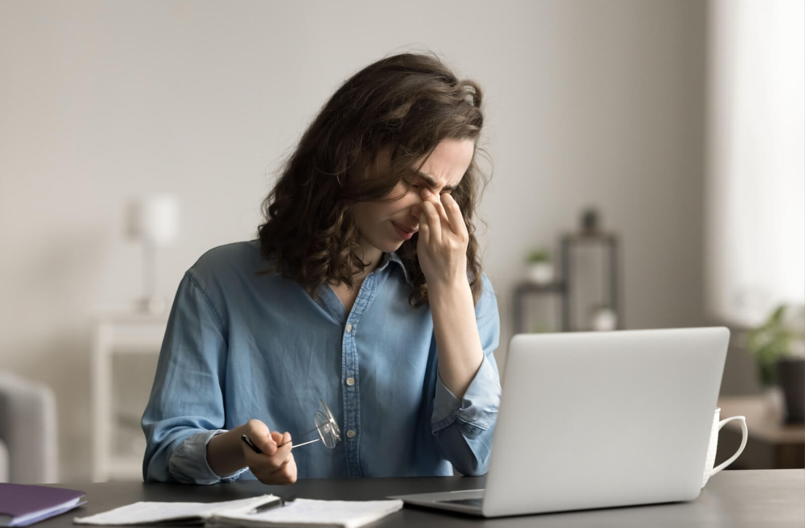 Adult experiencing eye strain and dry eye symptoms while working on a laptop, illustrating common causes of dry eyes such as prolonged screen time and digital eye fatigue.