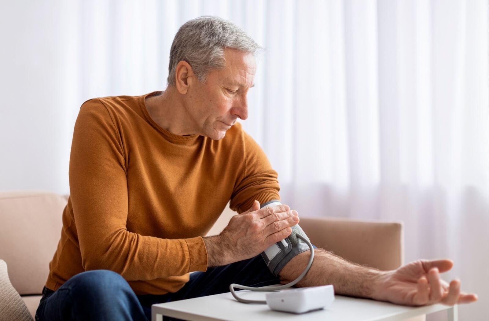 A senior checking his blood pressure at home, illustrating how retinal imaging can help detect systemic health issues like hypertension.